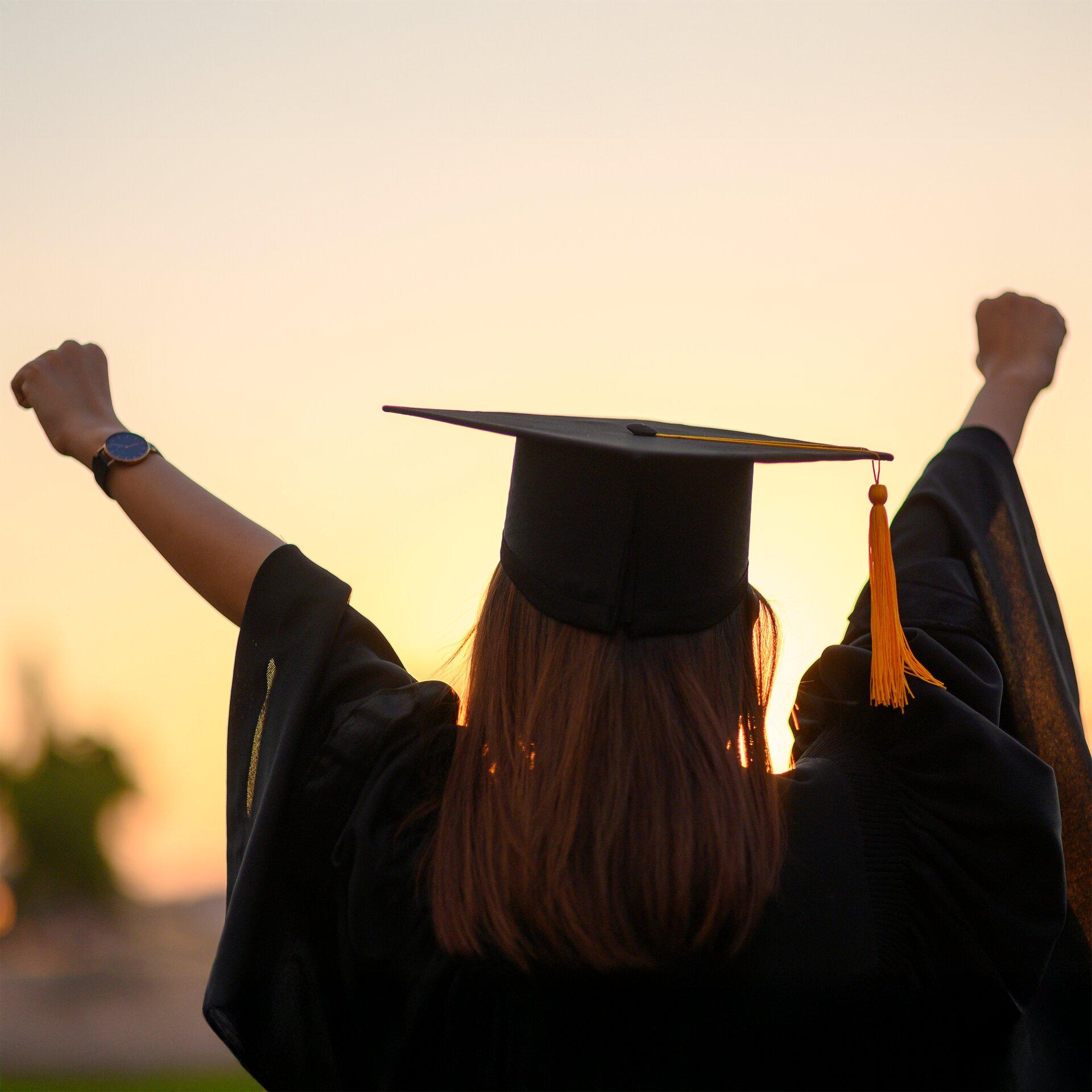 A woman in a graduation gown celebrating